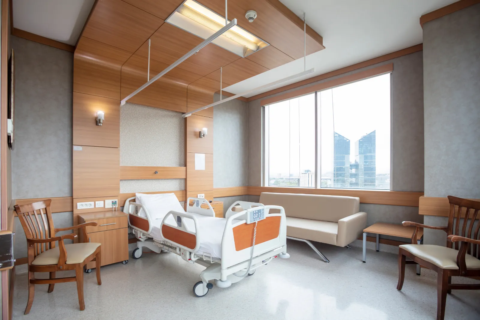 Cuarto privado de hospital con sofá para acompañante y vista a la ciudad